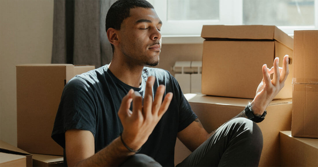 Men meditating in his room full of boxes